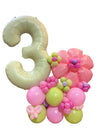 Balloon arrangement with number 3 and floral designs on a glass table.