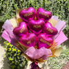 Bouquet of heart-shaped balloons with messages in a paper wrap, held against a blurred green background.