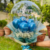 Bouquet of blue balloons in a transparent bubble with 'Happy Father's Day' text, held outdoors.