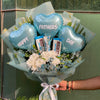 Bouquet with blue heart-shaped balloons and Hershey's chocolate bars, held by a person.