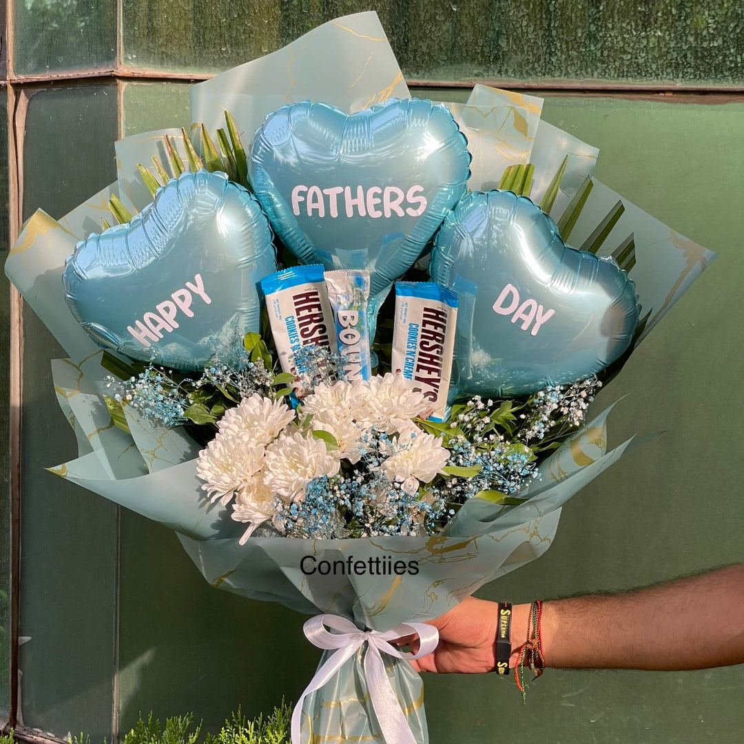 Bouquet with blue heart-shaped balloons and Hershey's chocolate bars, held by a person.