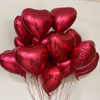Bouquet of red heart-shaped balloons against a neutral background