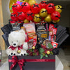 Gift basket with teddy bear, snacks, and balloons on a white surface.
