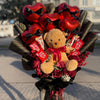 Bouquet with teddy bear, red roses, and chocolate bars on a street background