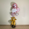 Bouquet of balloons with a teddy bear in front of a white wall