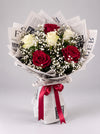 Scarlet & Ivory red and white rose bouquet with baby’s breath in newspaper-style wrapping and a red ribbon