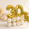 Gold '30' balloons with white pearls and a heart-shaped balloon on a light background