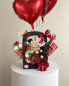 Close-up of the black gift basket with a teddy bear, chocolates, red and white flowers and burgundy ribbon.