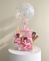 Pink floral gift arrangement with chocolates, a clear floral balloon and pink ribbon.