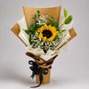 A bright sunflower takes centre stage among delicate white baby’s breath and green foliage. Kraft and ivory wrapping, tied with a black ribbon, give this cheerful bouquet a simple, warm finish for birthdays, congratulations and moments of appreciation.