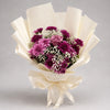 Rich purple and lavender chrysanthemums surround a purple rose, with white baby’s breath and green foliage adding texture. The bouquet is finished in ivory wrapping with a matching ribbon, making a thoughtful gift for birthdays, appreciation and special celebrations.
