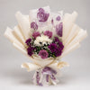 A graceful purple and ivory bouquet combining purple roses, purple and white chrysanthemums, delicate white baby’s breath and greenery. Layered ivory wrapping and a purple floral-print accent create a soft, elegant finish for birthdays, thank-you gifts and thoughtful celebrations.